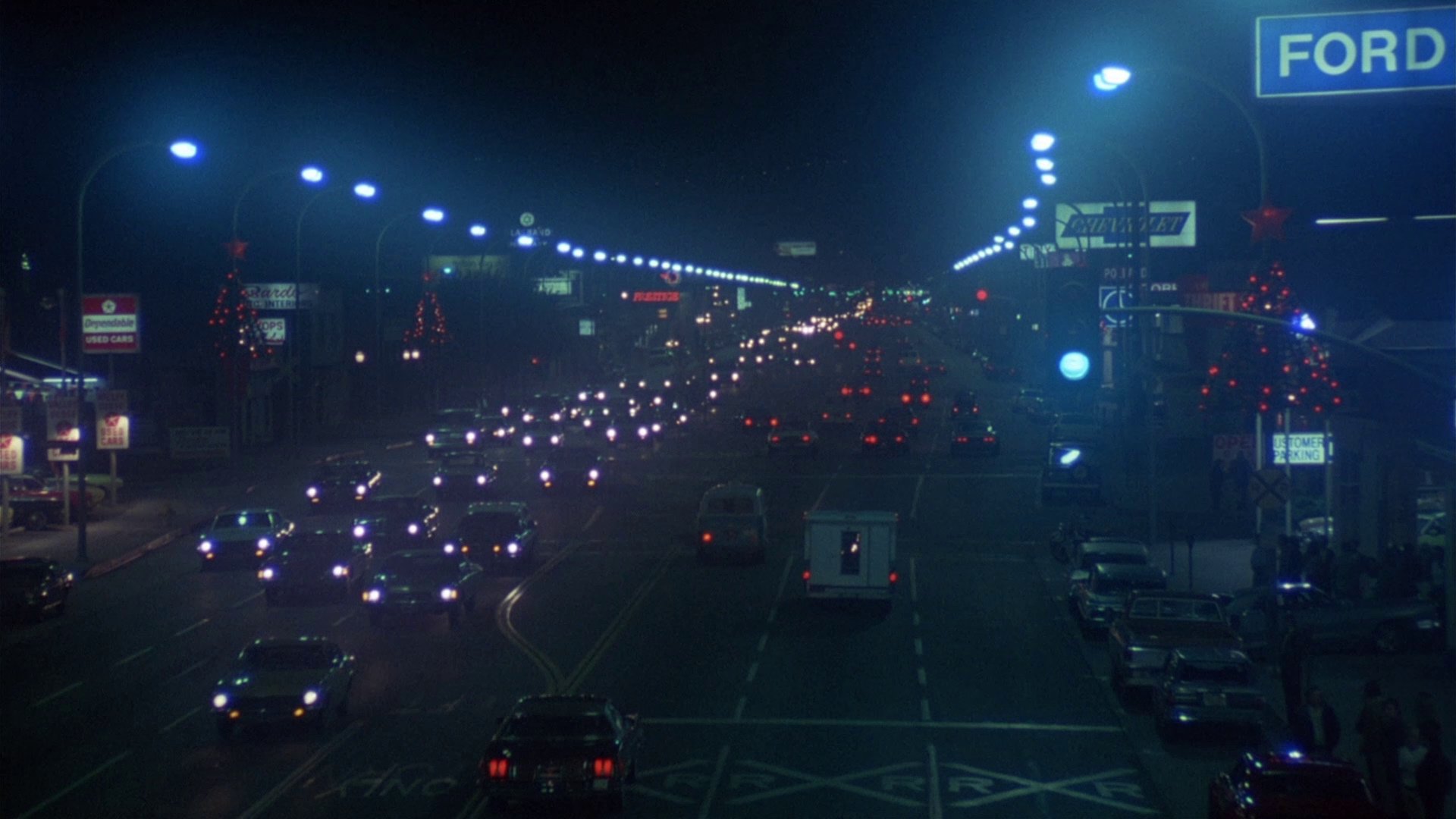 Traffic and glowing signs on a Los Angeles thoroughfare at night, as seen in Aloha, Bobby and Rose (1975).